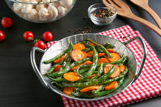 Delicious green beans and carrot slices in frying pan on kitchen table