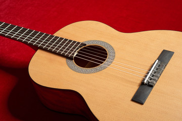 Fototapeta na wymiar acoustic guitar on red velvet fabric, closeup object