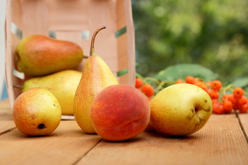 Pears, peach and rowan berries in a wooden box on a wooden table when harvesting in the forest