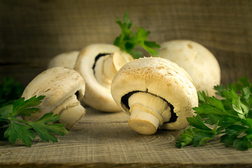 White mushrooms champignons, parsley, old wooden table