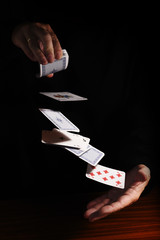 throwing cards from one hand to the other against a black background with copy space, business metaphor or concept for new start, destiny, and gamble, copy space, vertical