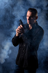 detective or criminal with gun on foggy night background