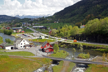 Fototapeta na wymiar View from Steinsdalsfossen waterfall at the river of Steine - scenic landscape with cascade surounded by mountains and traditional norvegian, scandinavian houses