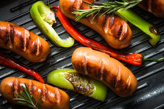 Fried sausages with  vegetables in grill pan at black background