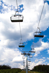 Mountain chair ski lift at blue sky with white clouds