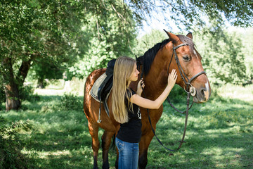 Beautiful girl gently hugs her friend - brown horse