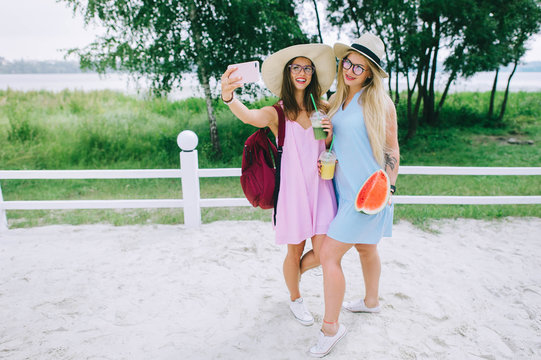 Two happy girls drink juice