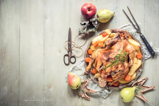 Whole roasted turkey with vegetables and fruits on wooden background with blank space
