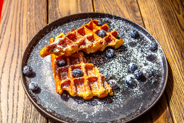 Viennese waffles with berry sauce and creme fraiche are on the plate.