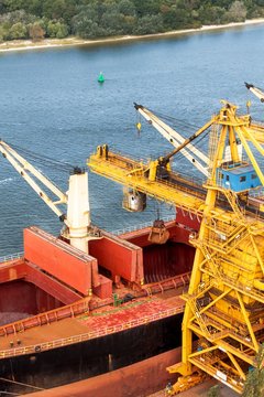 Crane Unloads Iron Ore At The Harbor. Trade In Raw Materials. Work At A Port In The Baltic Sea.