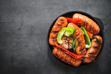 Fried bbq sausages with  vegetables at black slate table. Top view copy space.