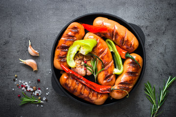 Fried bbq sausages with  vegetables at black slate table.