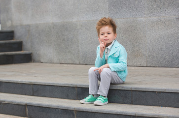 Fashion kid posing near gray wall