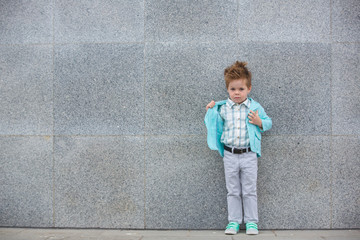 Obraz na płótnie Canvas Fashion kid posing near gray wall