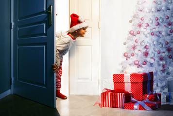 Boy checking presents under Christmas tree