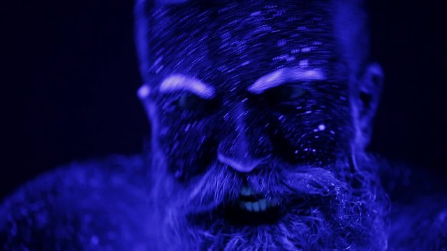 A terrible bearded man in ultraviolet light. Close-up of a face.