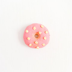 One pink donut on white background. Flat lay, top view minimal concept.