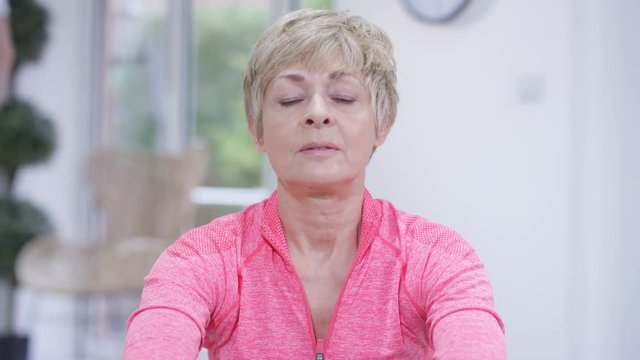  Healthy active mature woman working out on rowing machine at the gym