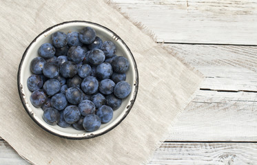 ripe plums in a bowl on a light background