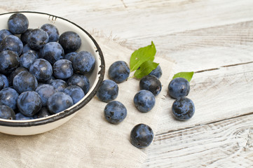 ripe plums in a bowl on a light background