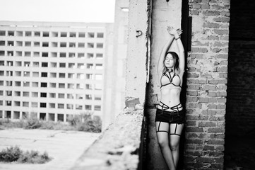 Girl wear on shorts and black erotic fetish underwear at abadoned factoty with brick.