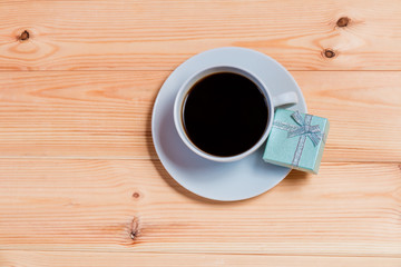 Cup of coffee and gift box on wooden background