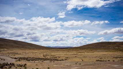 Fototapeta na wymiar High altitude landscape with harsh barren landscape and scenic dramatic sky. Wide angle view from above at 4000 m on the Andean highlands, Peru.