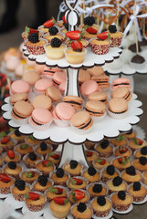 Delicious sweets, cupcakes, macaroons on white stand. wedding candy bar.