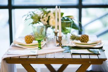 table decorated with plates, pineapples, candles and flowers, green and white colour