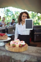 Waitress showing digital tablet at outdoor café