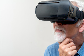 Mature man wearing Virtual Reality glasses, VR headset for use with smart phone