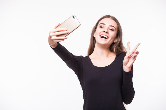 Gorgeous young woman in street style clothes taking selfie with mobile phone isolated over white background