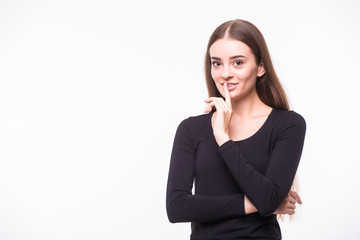 Portrait of funny young Caucasian woman in white shirt and glasses with hair bun holding index finger at lips, asking to keep silence or not tell anyone her secret, raising brows, saying 'shh'.