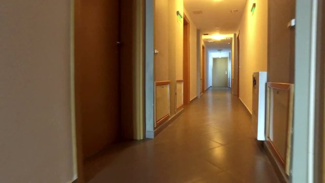 Walking pov in hotel hallway with many doors. Reaching the 