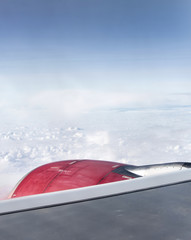 red jet engine turbine look through aircraft window on sunny day blue sky clouds
