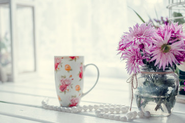 Pink flowers with cup of tea near the window