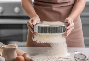 Female chef sifting flour onto kitchen table