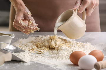 Female chef making dough on kitchen table