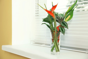 Beautiful tropical flowers in vase on window sill