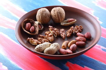 Walnuts and peanuts on a brown clay plate on a pop art background
