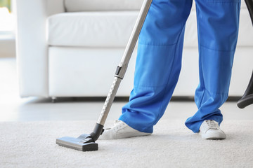 Man cleaning white carpet with vacuum in living room
