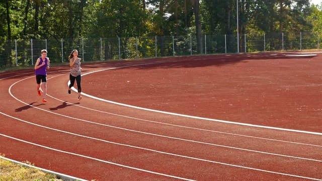 Track runners man wand woman running on stadium, 4k