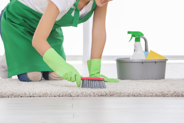 Woman cleaning carpet with brush indoors