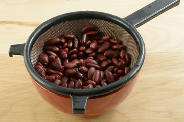 Canned kidney beans in strainer to drain after rinsing with water to reduce sodium