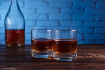 Two glasses of whiskey and a bottle on wooden table, copy space.  Alcohol drinks, bar concept