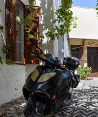 Motorbike parked near wall with beautiful window in Rhodes town on Rhodes island, Greece