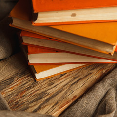 A stack of paper books in orange color on textured wooden surface. Autumn mood concept. Time to...