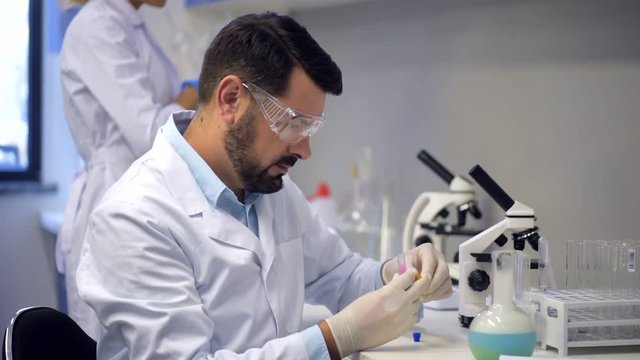 Mature chemist dropping litmus paper into test tube