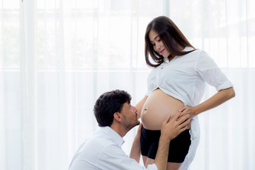 close up husband kiss pregnant woman belly - love of father to the unborn child.
