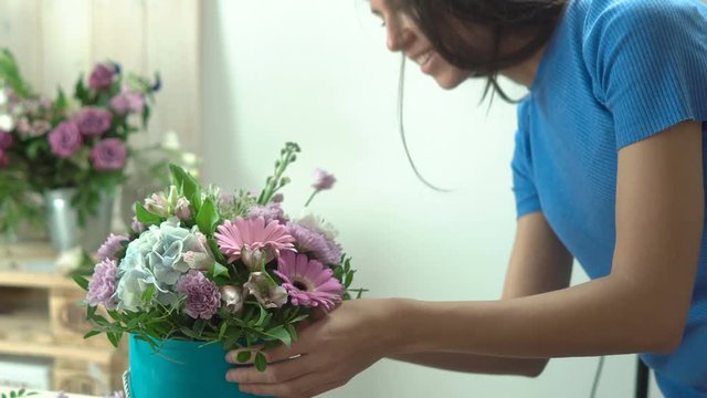 Attractive woman florist in the process of making a hat box with flowers close-up 4k.